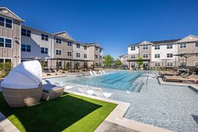 Spring apartment for rent - a swimming pool with lounge chairs and umbrellas in front of an apartment building