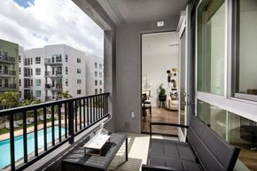 Santa Ana apartment for rent - A balcony with a black couch and a pool in the background.