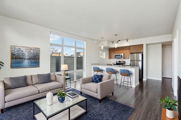 Seattle apartment for rent - A living room with a grey couch, a glass coffee table, and a painting on the wall.
