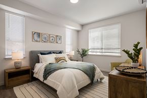 Kennewick apartment for rent - A bedroom with a bed, nightstand, and a plant.
