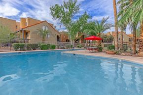 Tucson apartment for rent - A swimming pool in front of a house with a red umbrella.