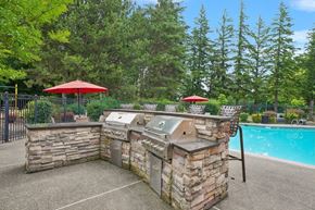 Gresham apartment for rent - A backyard with a pool and a stone barbecue.