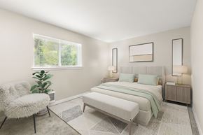 Port Orchard apartment for rent - A bedroom with a large bed, a chair, and a potted plant.
