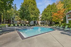 Everett apartment for rent - A swimming pool surrounded by trees and lounge chairs.