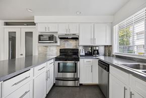 Tacoma apartment for rent - A modern kitchen with white cabinets and stainless steel appliances.