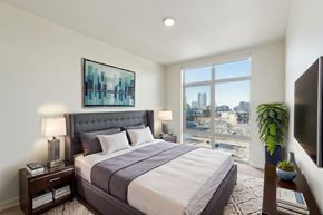 Seattle apartment for rent - A bedroom with a large bed and a city view through the window.