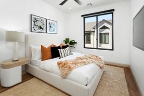 Phoenix apartment for rent - A bedroom with a large bed and a window overlooking a house.