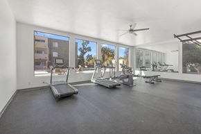 Tucson apartment for rent - A spacious home gym with treadmills, elliptical machines, and a fan.