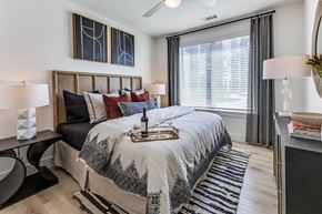 Austin apartment for rent - A bedroom with a large bed and a window with blinds.
