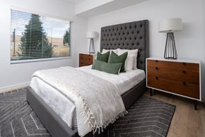 Layton apartment for rent - A bedroom with a large bed, a wooden dresser, and two lamps.
