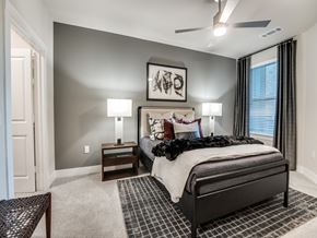 Dallas apartment for rent - A bedroom with a large bed, a ceiling fan, and a painting on the wall.