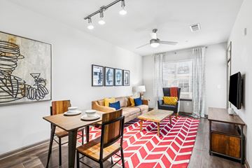 Nashville apartment for rent - A living room with a red and white rug and a painting of a cocktail glass on the wall.