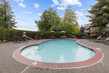 Outdoor pool with sun loungers and umbrella table seating