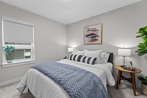 Seattle apartment for rent - A bedroom with a large bed and a small table with a lamp on it.