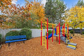 Kent apartment for rent - A playground with a red and yellow swing set and a blue bench.