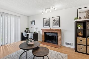 Renton apartment for rent - A living room with a fireplace and a table with a plant on it.