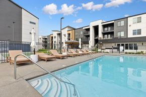 Pasco apartment for rent - A swimming pool with sun loungers and apartment buildings in the background.