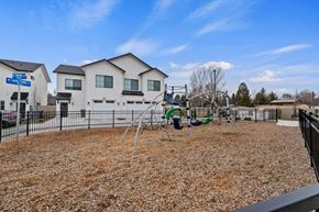 Garden City apartment for rent - A playground with a swing set and a play area in front of a building.