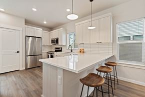 Garden City apartment for rent - A kitchen with white cabinets and a white island with three stools.