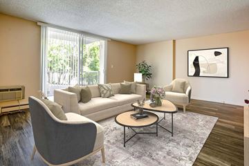 Spokane apartment for rent - A living room with a grey armchair, a white sofa, a coffee table, and a painting on the wall.