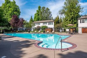 Eugene apartment for rent - A large outdoor swimming pool surrounded by trees and a white building.