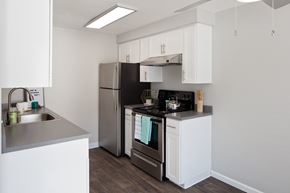 Gresham apartment for rent - A kitchen with a black refrigerator and stove top oven.