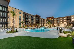 Austin apartment for rent - A swimming pool surrounded by a grassy area and apartment buildings.