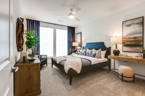 Plano apartment for rent - A bedroom with a bed, nightstand, and a painting on the wall.