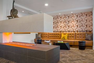 Phoenix apartment for rent - A modern living room with a brown sofa and a wooden sculpture on the wall.