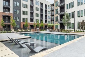 Plano apartment for rent - A swimming pool surrounded by modern buildings and lounge chairs.