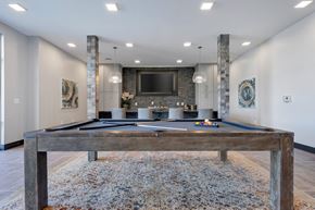 O Fallon apartment for rent - A pool table in a room with a stone pillar and a television mounted on the wall.