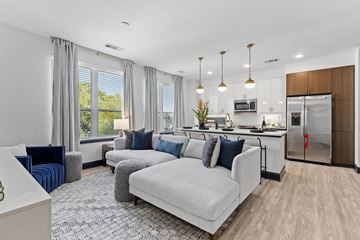 Atlanta apartment for rent - A modern living room with a grey sofa set and a kitchen in the background.