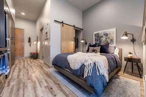 Seattle apartment for rent - A bedroom with a bed covered in a blue comforter and a white fur throw.