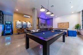 Seattle apartment for rent - A pool table is in the middle of a room with a foosball table to the left and a shuffleboard table in the background.