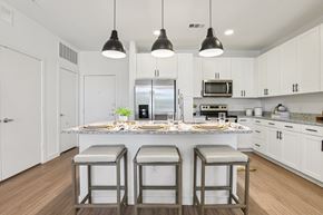 Austin apartment for rent - A kitchen with white cabinets and a center island with two stools.