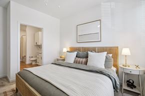 Austin apartment for rent - A bedroom with a large bed and a small table with a lamp.
