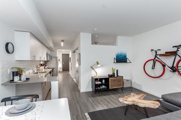 Bothell apartment for rent - A modern living room with a grey sofa and a white dining table.