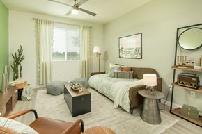 Glendale apartment for rent - A bedroom with a bed, a chair, a table, and a ceiling fan.