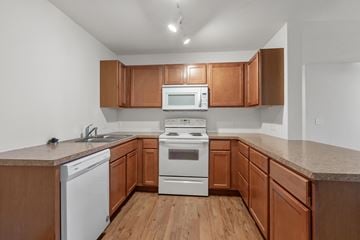 Coeur Dalene apartment for rent - A kitchen with wooden cabinets and white appliances.