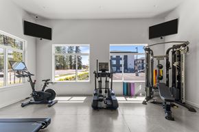 Spokane apartment for rent - A spacious home gym with a variety of equipment including a treadmill, stationary bike, and weight machines.