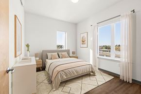 Seattle apartment for rent - A bedroom with a large bed and a view of the outdoors through the window.