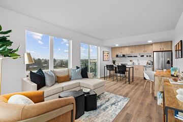 Seattle apartment for rent - a living room with a couch and a chair and a kitchen with a large window