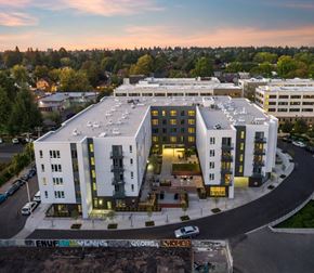 Portland apartment for rent - A modern building with a curved design is surrounded by a parking lot.