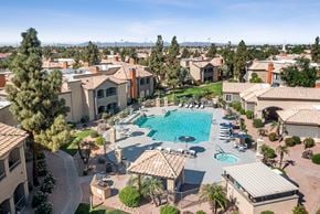Gilbert apartment for rent - A large swimming pool surrounded by houses and trees.