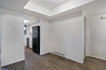 Holladay apartment for rent - A black refrigerator sits in a kitchen with white walls and wood floors.