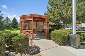 Broomfield apartment for rent - A wooden gazebo is surrounded by green bushes and a stone wall.