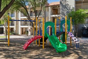 Tucson apartment for rent - A playground with a green slide and a red slide in front of a building.