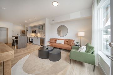 Liberty Lake apartment for rent - A living room with a green couch and a round mirror on the wall.