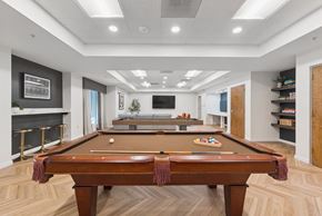 Dallas apartment for rent - A pool table is in the middle of a room with a fireplace and a TV.