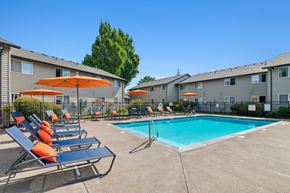 Corvallis apartment for rent - A pool area with sun loungers and umbrellas in front of apartment buildings.